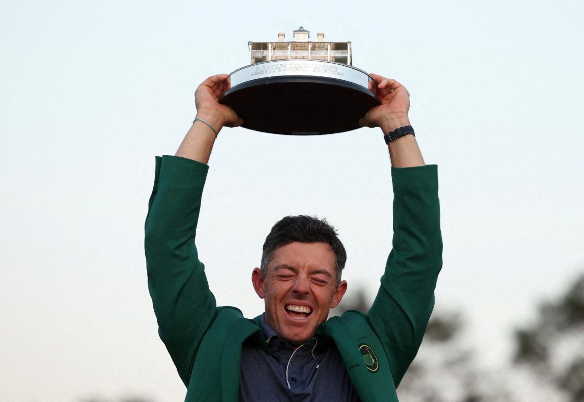 Golf - The Masters - Augusta National Golf Club, Augusta, Georgia, U.S. - April 13, 2025 Northern Ireland's Rory McIlroy celebrates with his green jacket and the trophy after winning The Masters and completing a career grand slam REUTERS/Pilar Olivares