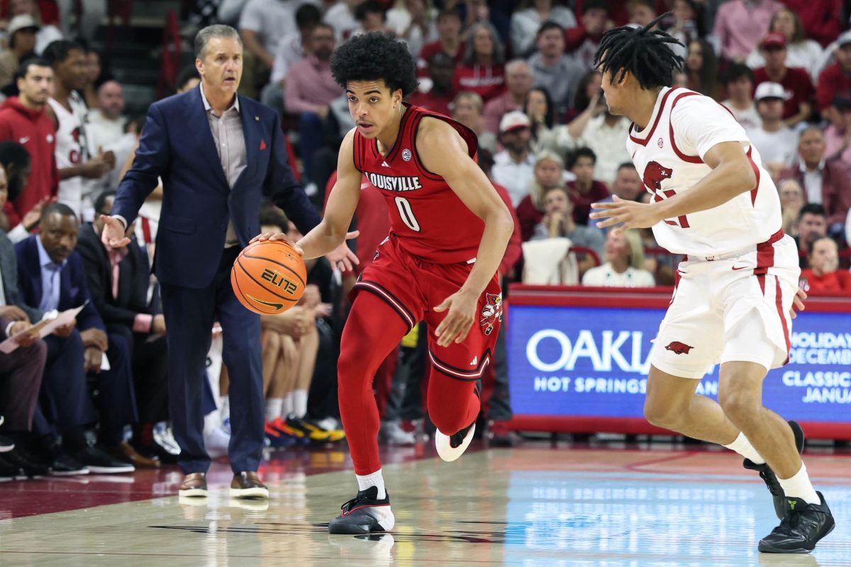 Dec 3, 2025; Fayetteville, Arkansas, USA; Louisville Cardinals guard Mikel Brown Jr (0) drives against Arkansas Razorbacks guard D.J. Wagner (21) as head coach John Calipari watches during the second half at Bud Walton Arena. Arkansas won 89-80. Nelson Chenault-Imagn Images