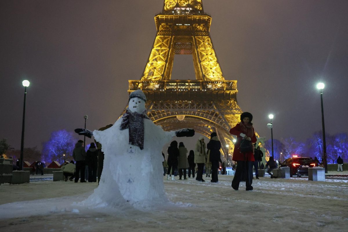 People walk in the snow-covered Pont Iena bridge near the Eiffel Tower, as winter weather with snow and cold temperatures hits a large part of the country, in Paris, France, January 5, 2026. REUTERS/Gonzalo Fuentes